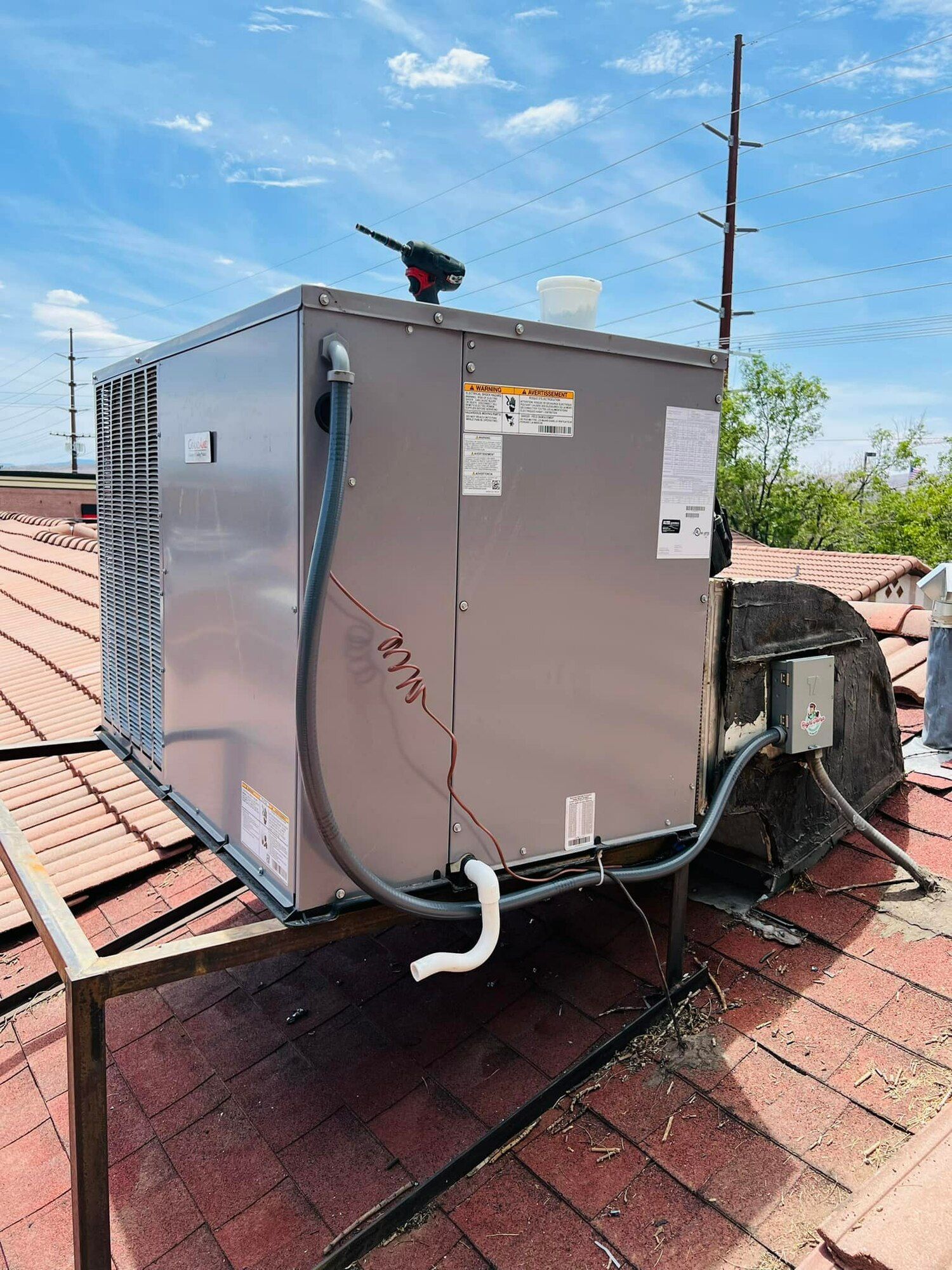 A large air conditioner is sitting on top of a brick roof.