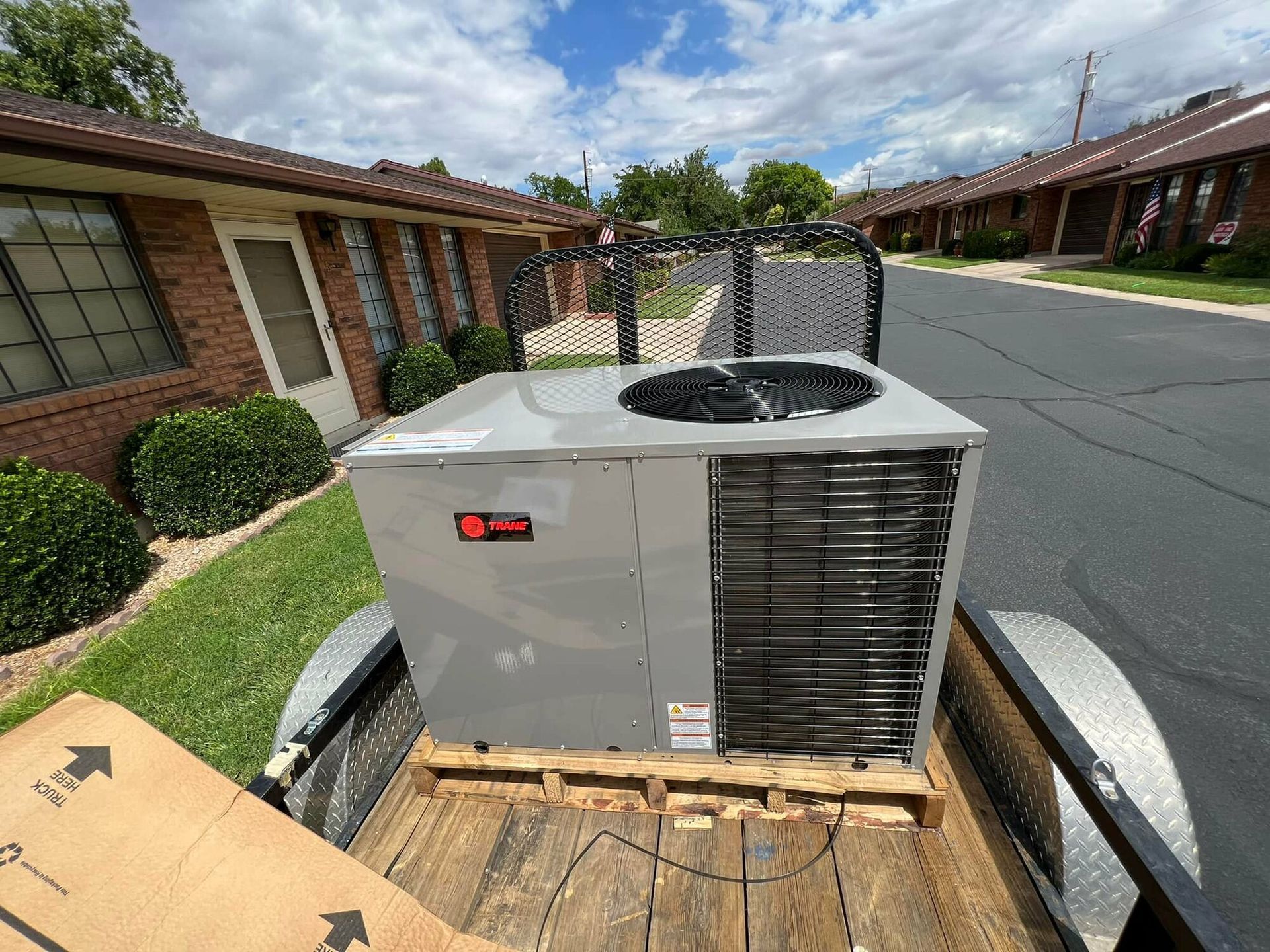 A large air conditioner is sitting on top of a wooden pallet in the back of a trailer.