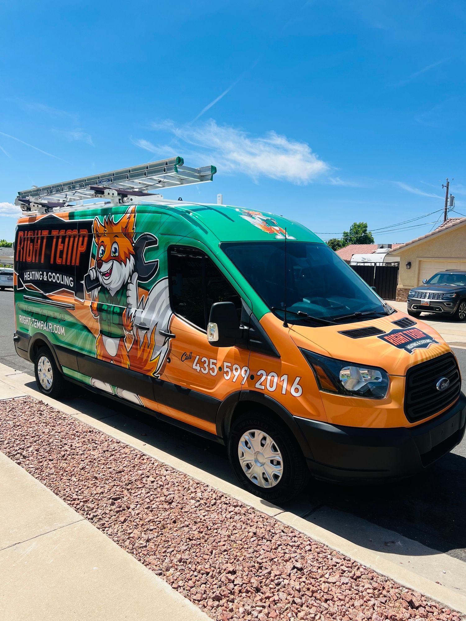 A green and orange van with a fox on the side is parked on the side of the road.