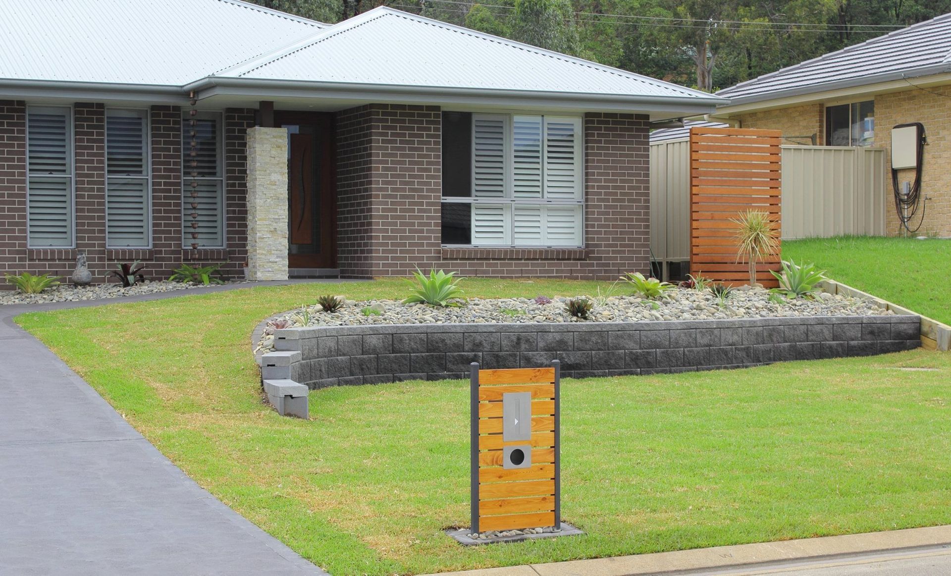 A Brick House With a Lush Green Lawn — Seascapes Landscape Construction in Kendall, NSW