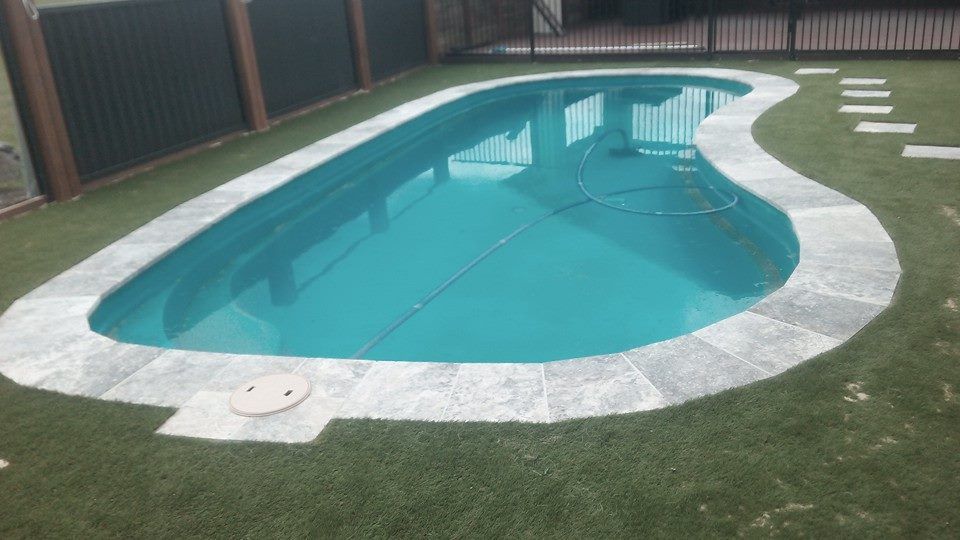 A Large Swimming Pool is Surrounded by Grass and a Fence — Seascapes Landscape Construction in Kendall, NSW