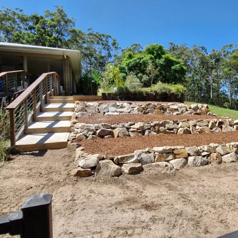 A House With Stairs Leading Up to It and a Rock Wall in Front of It — Seascapes Landscape Construction in Kendall, NSW