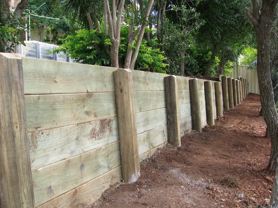 A Wooden Fence is Surrounded by Trees and Dirt — Seascapes Landscape Construction in Kendall, NSW