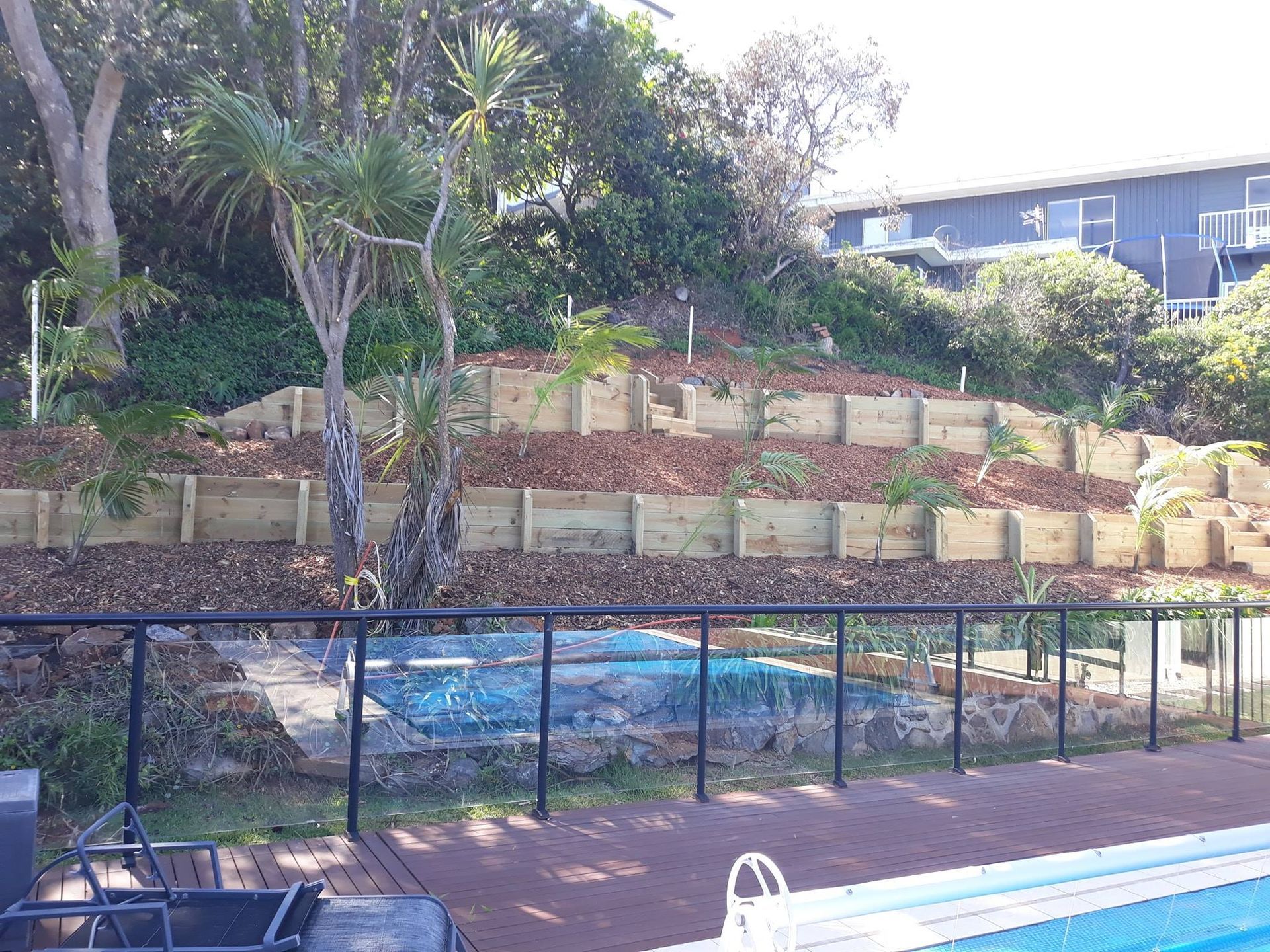 A Swimming Pool is Surrounded by a Wooden Fence and a Wooden Wall — Seascapes Landscape Construction in Port Macquarie, NSW