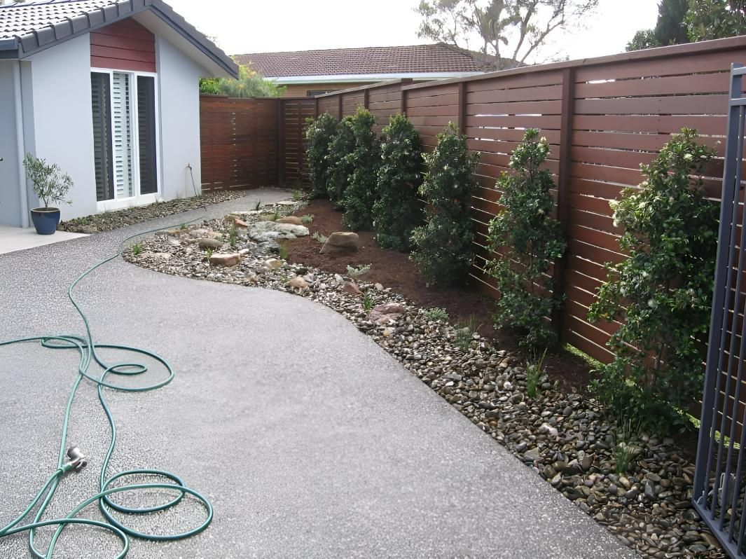 A Hose is Laying on the Ground in Front of a House — Seascapes Landscape Construction in Kendall, NSW