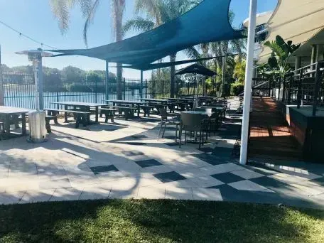 A Patio With Tables and Chairs Under a Blue Umbrella — Seascapes Landscape Construction in Kendall, NSW