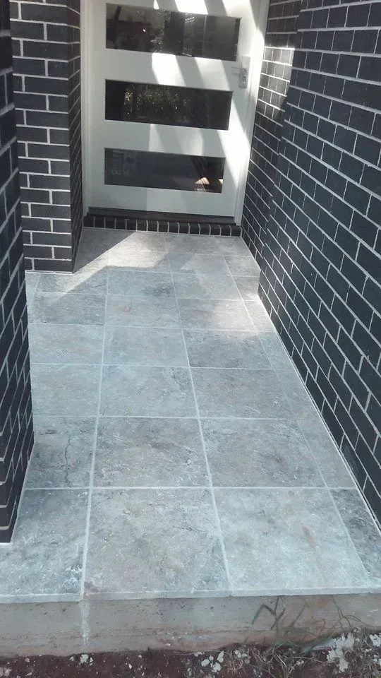 A Brick Wall With a Tiled Walkway Leading to a Door — Seascapes Landscape Construction in Kendall, NSW