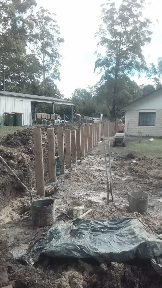 A Wooden Fence is Being Built in the Dirt in Front of a House — Seascapes Landscape Construction in Kendall, NSW