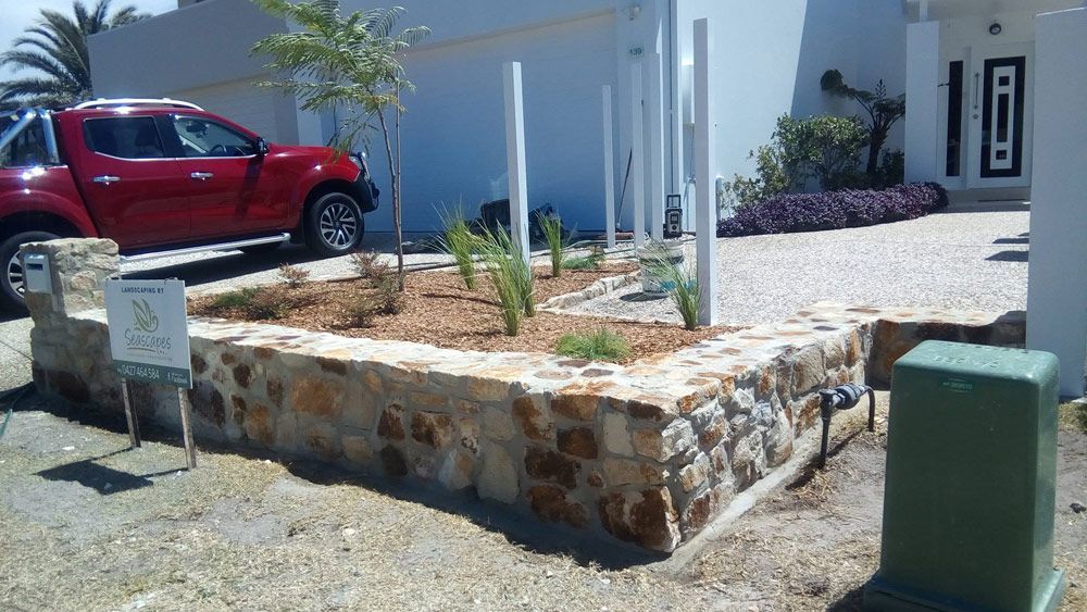 A Red Truck is Parked in Front of a White House — Seascapes Landscape Construction in Port Macquarie, NSW