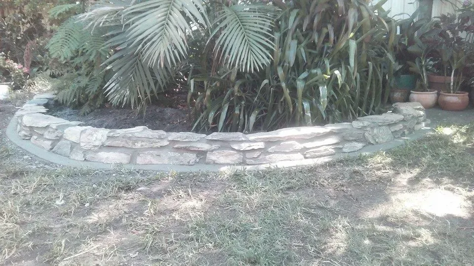 A Stone Border in a Garden With a Palm Tree in the Background — Seascapes Landscape Construction in Kendall, NSW