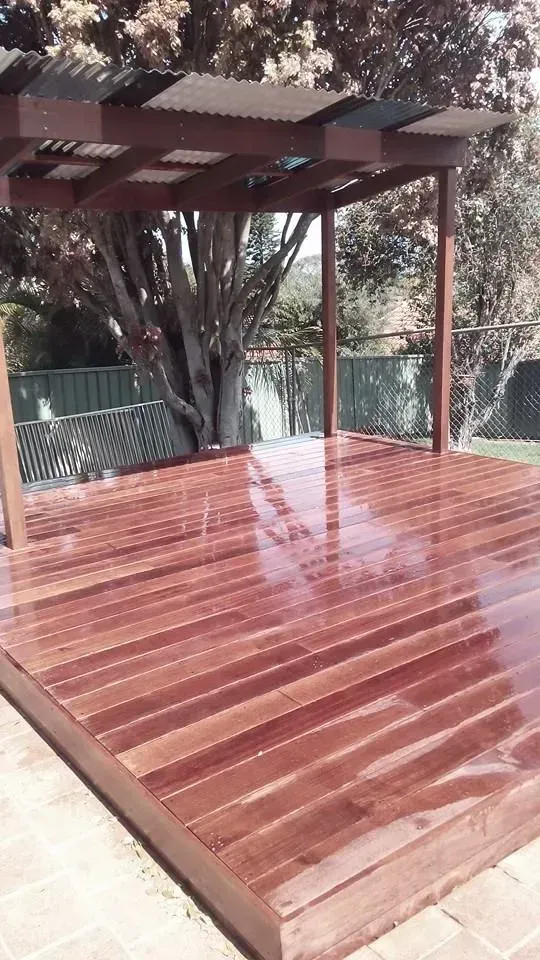 A Wooden Deck With a Pergola and a Tree in the Background — Seascapes Landscape Construction in Kendall, NSW