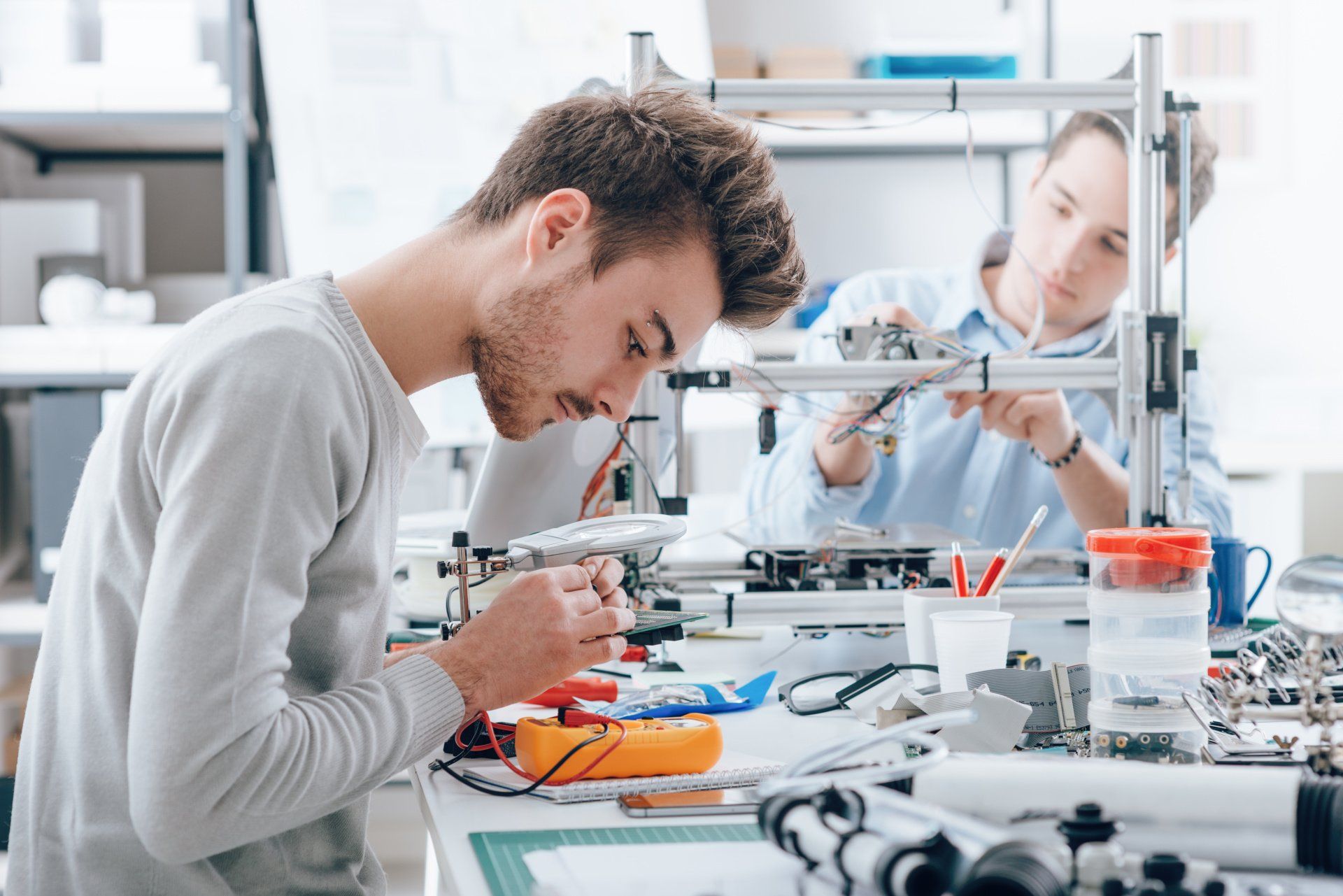 A man and a woman are working on electronics in a lab.