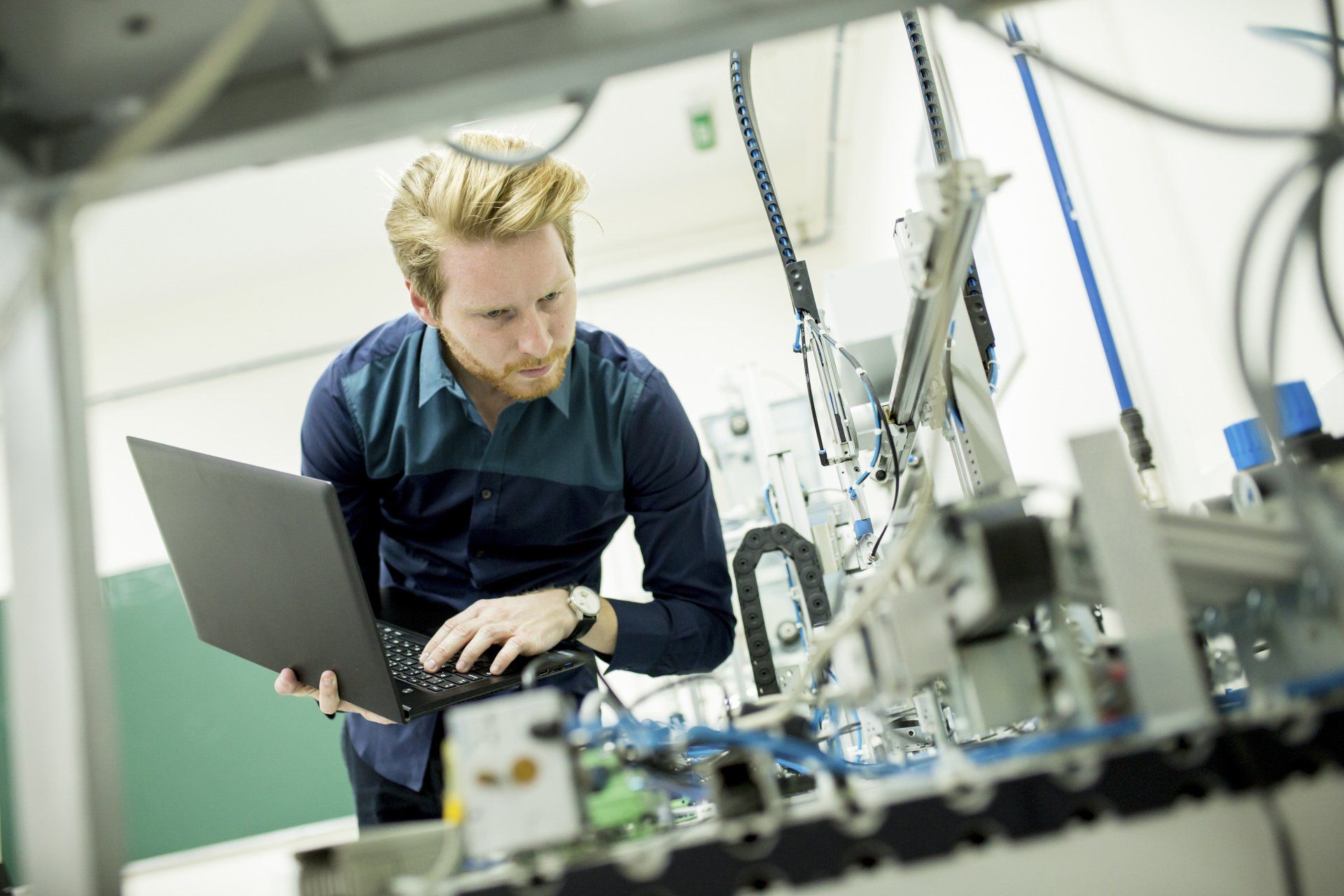 A man is using a laptop computer in a factory.