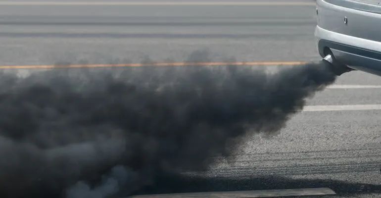 A car is emitting black smoke from its exhaust pipe.