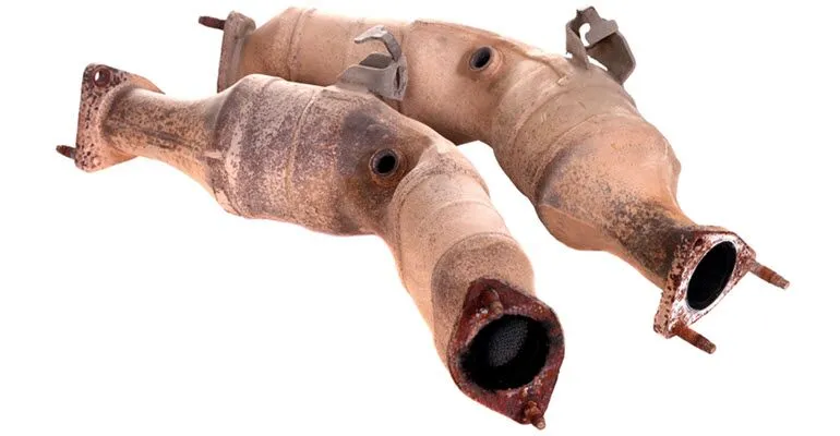 A pair of rusty catalytic converters on a white background.