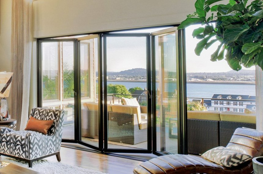 A living room with a lot of windows and a view of the ocean.