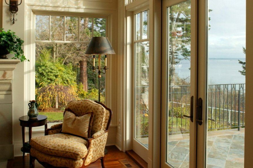 A living room with a chair , lamp , table and sliding glass doors.