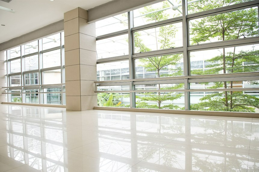 A large empty room with lots of windows and trees in the background.