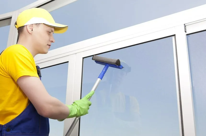 A man is cleaning a window with a squeegee.
