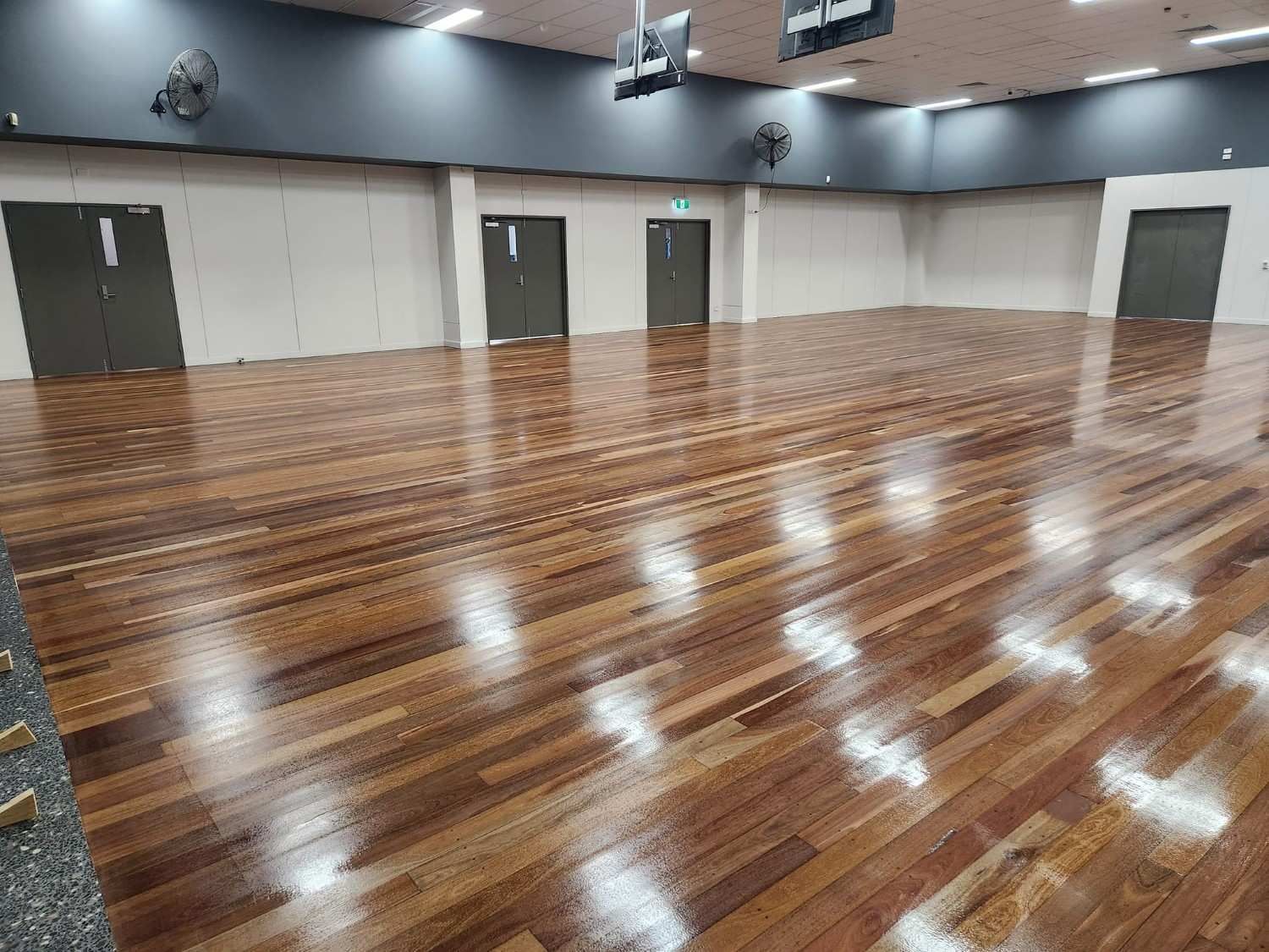 A Large Empty Room with A Wooden Floor and Doors — Finish It Floor Sanding in Bucca, QLD