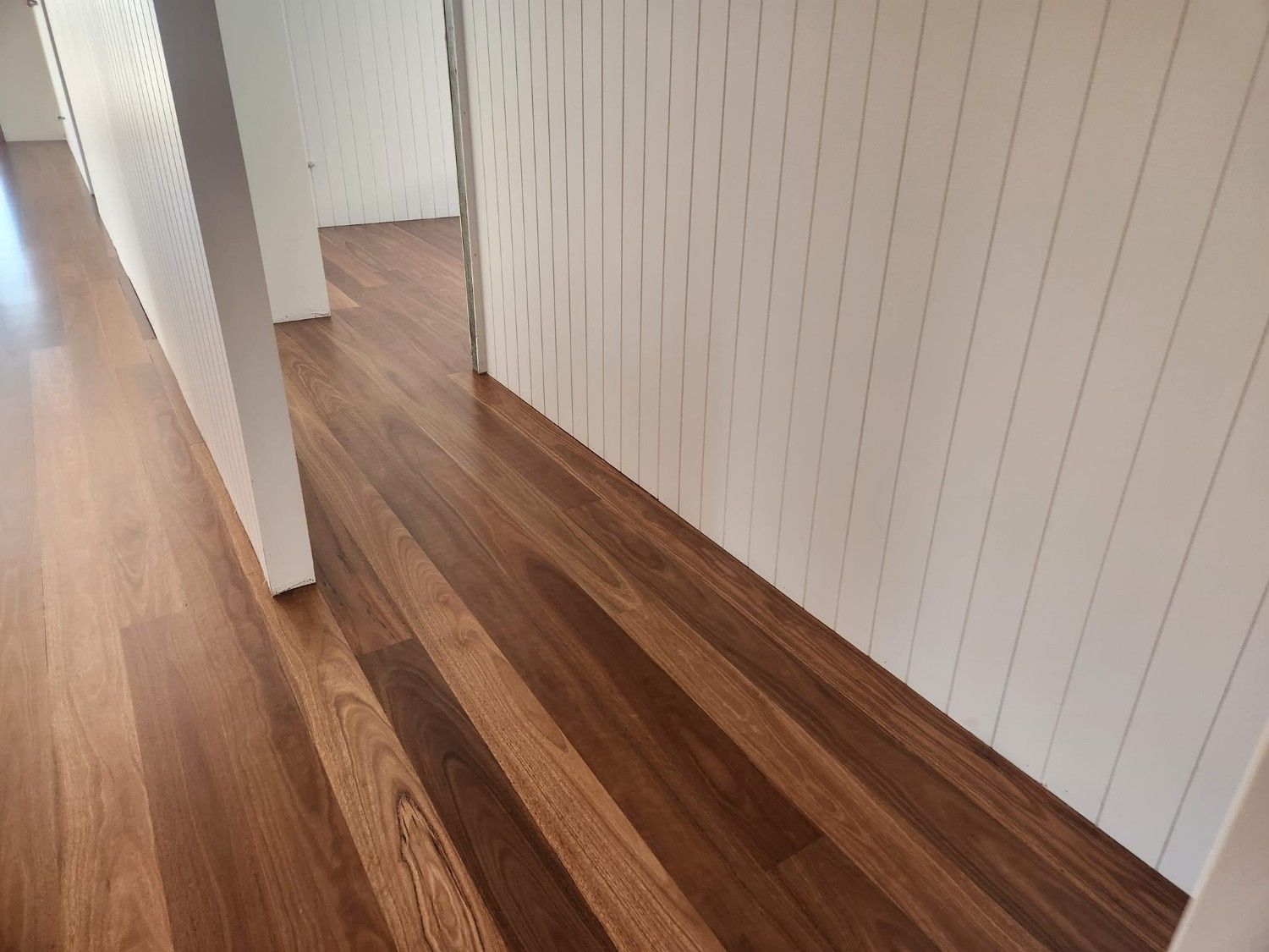 A Hallway with Hardwood Floors and White Walls — Finish It Floor Sanding in Bundaberg, QLD