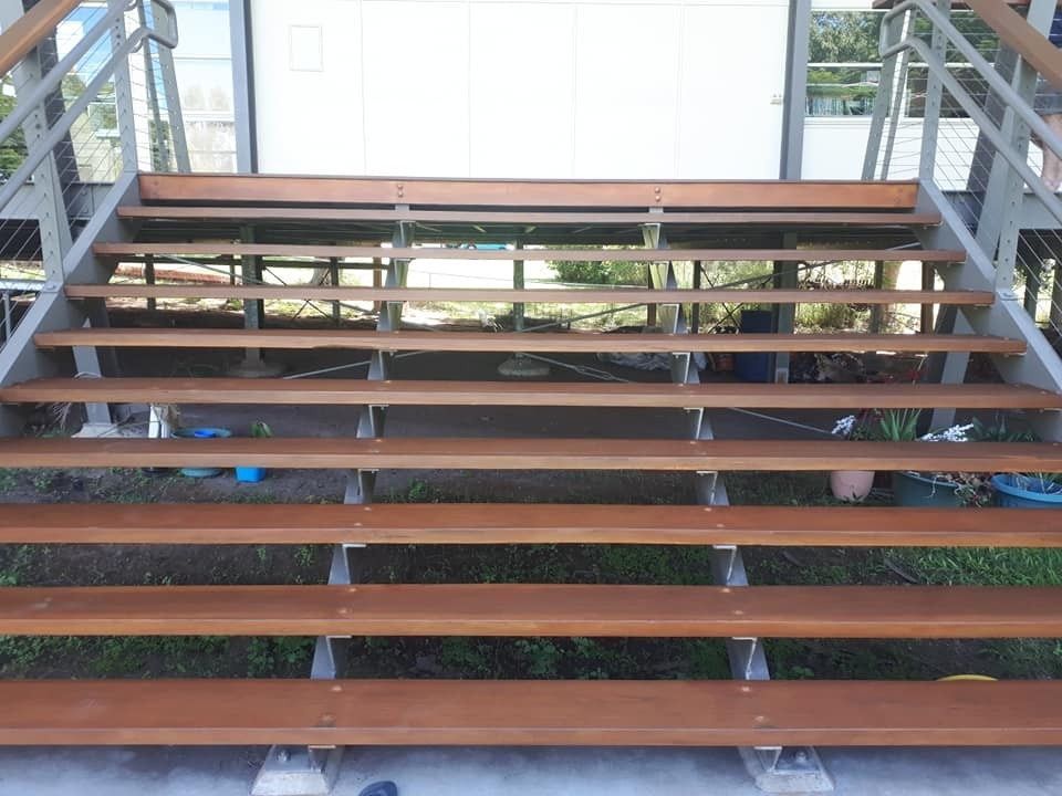 A Set of Wooden Stairs with A Metal Railing Leading up To a House — Finish It Floor Sanding in Bucca, QLD