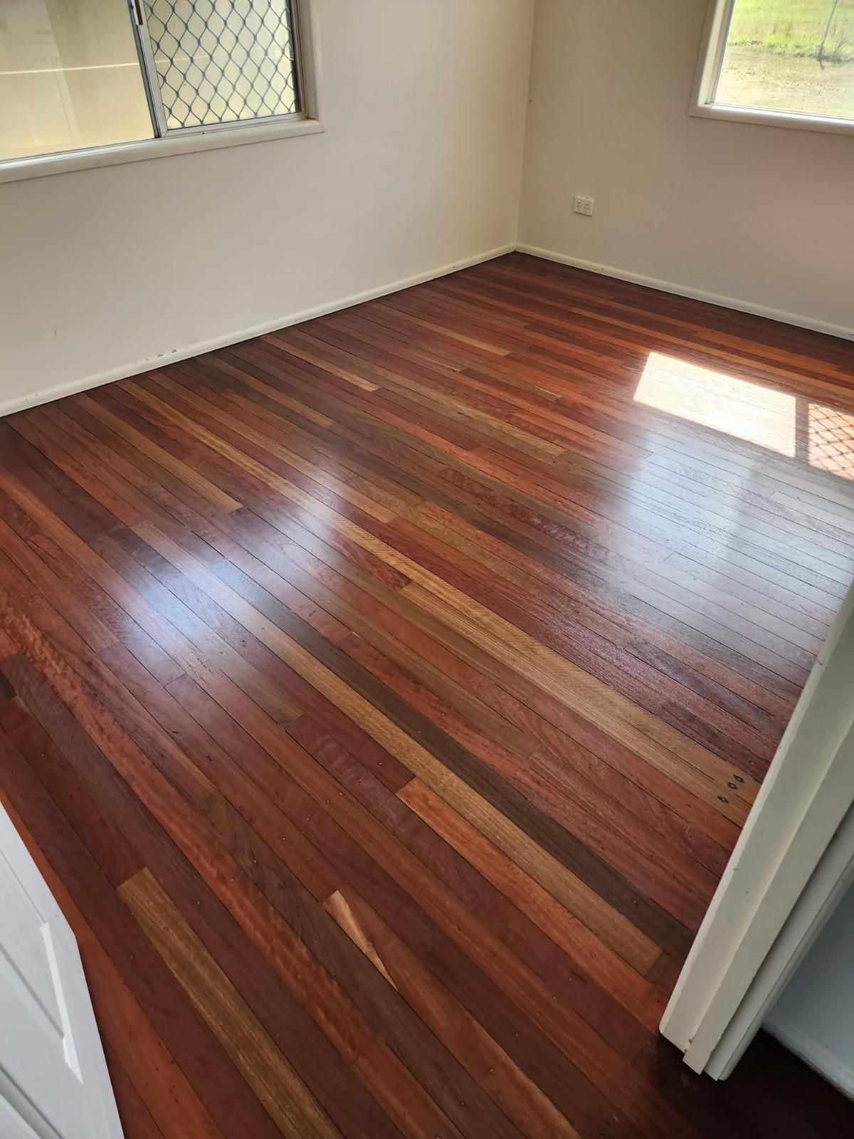 A Bedroom with A Wooden Floor and A Window — Finish It Floor Sanding in Bucca, QLD