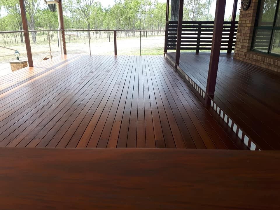 A Large Wooden Deck with A Brick Building in The Background — Finish It Floor Sanding in Mundubbera, QLD