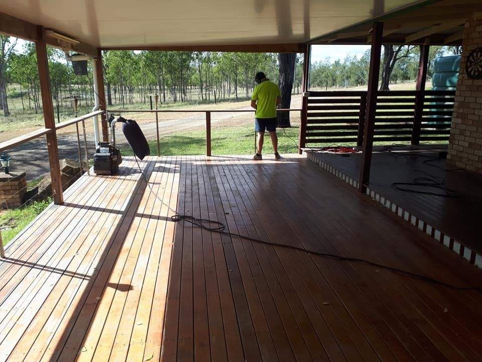 A Man in A Yellow Shirt Is Standing on A Wooden Deck — Finish It Floor Sanding in Mundubbera, QLD