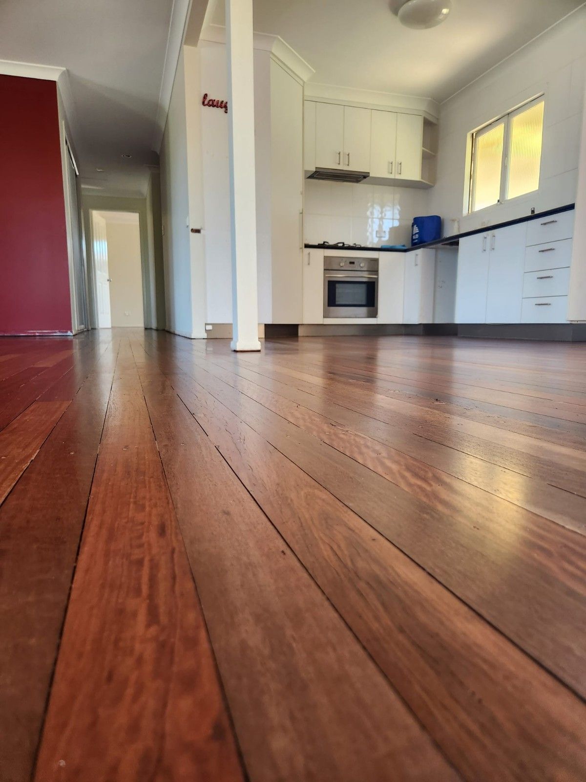 A Kitchen with A Wooden Floor and White Cabinets — Finish It Floor Sanding in Bucca, QLD