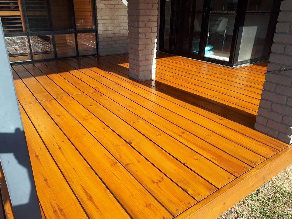 A Wooden Deck with A Brick Wall in The Background — Finish It Floor Sanding in Mundubbera, QLD