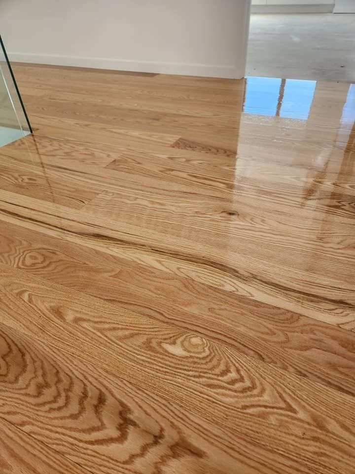 A Close up Of a Wooden Floor with A Glass Railing — Finish It Floor Sanding in Bucca, QLD