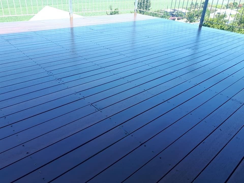A Wooden Deck with A Glass Railing and A View of A Field — Finish It Floor Sanding in Bucca, QLD