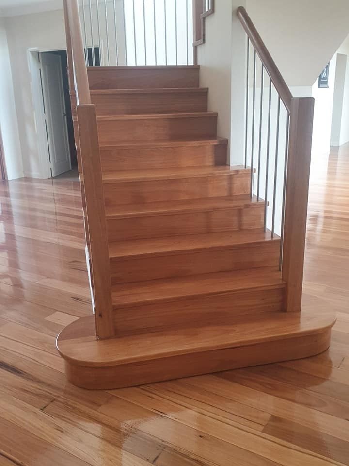 A Wooden Staircase with A Metal Railing in A Room with Hardwood Floors — Finish It Floor Sanding in Bucca, QLD