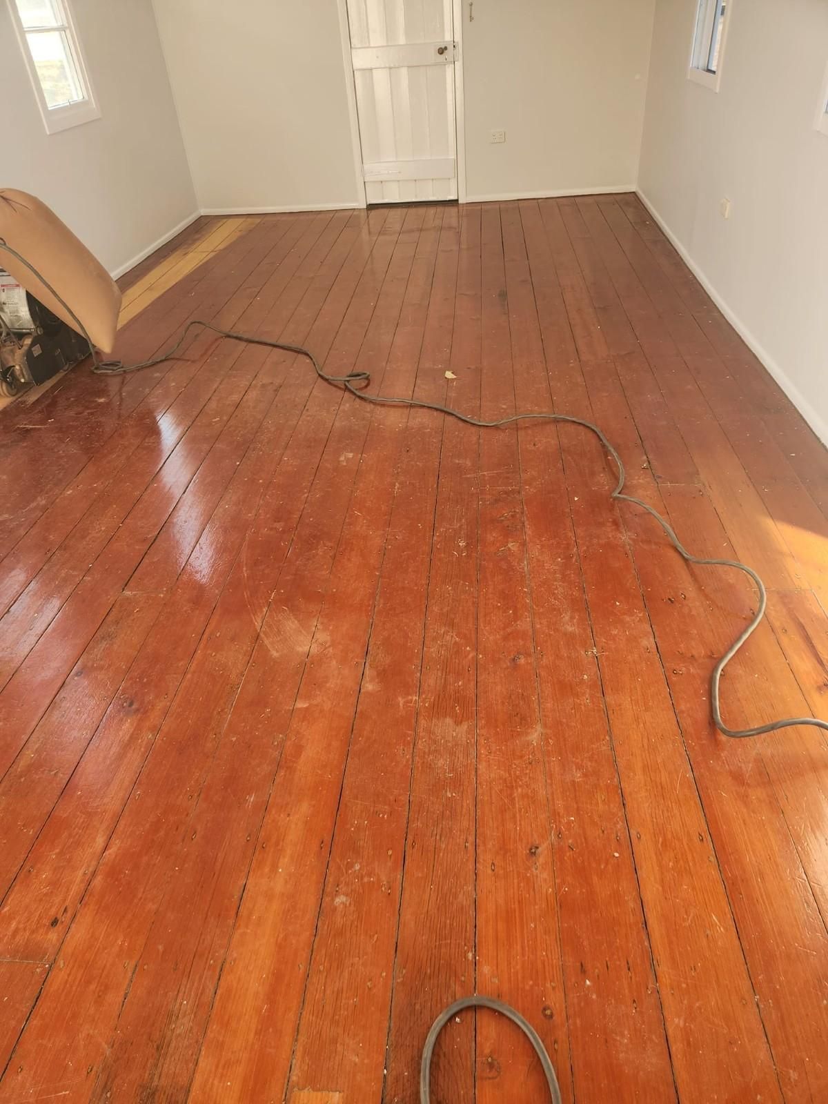 A Room with A Wooden Floor and A Vacuum Cleaner on It — Finish It Floor Sanding in Bucca, QLD