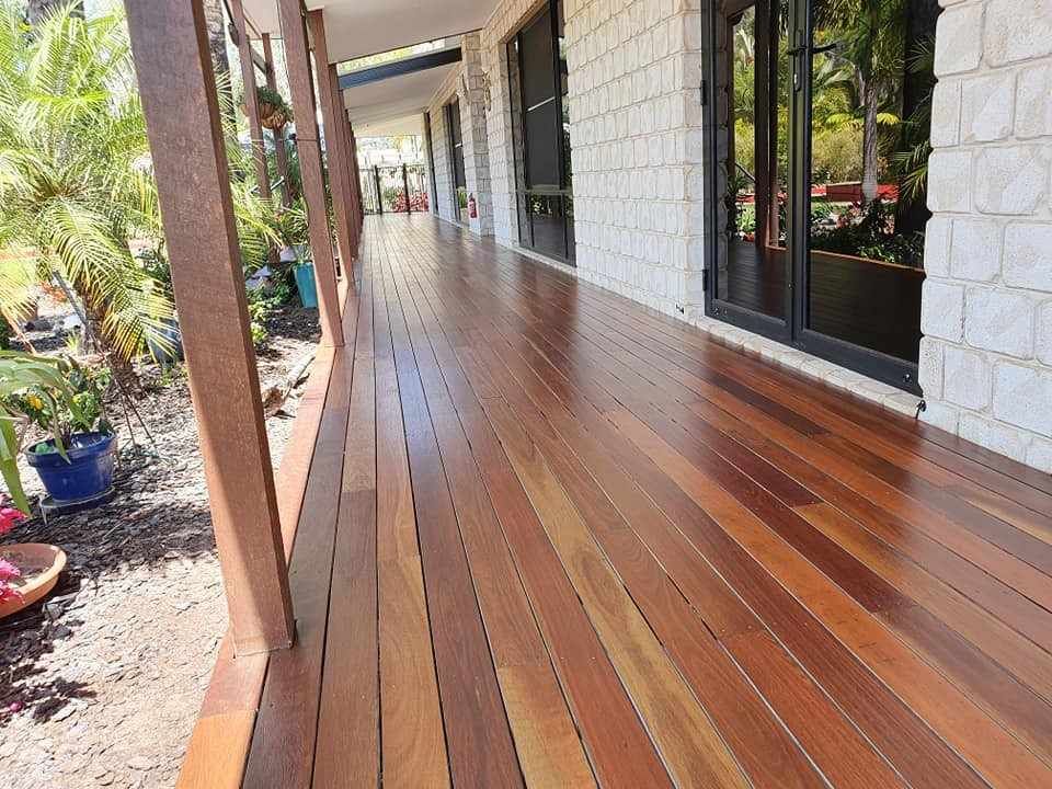 A Wooden Deck with A Brick Building in The Background — Finish It Floor Sanding in Bucca, QLD