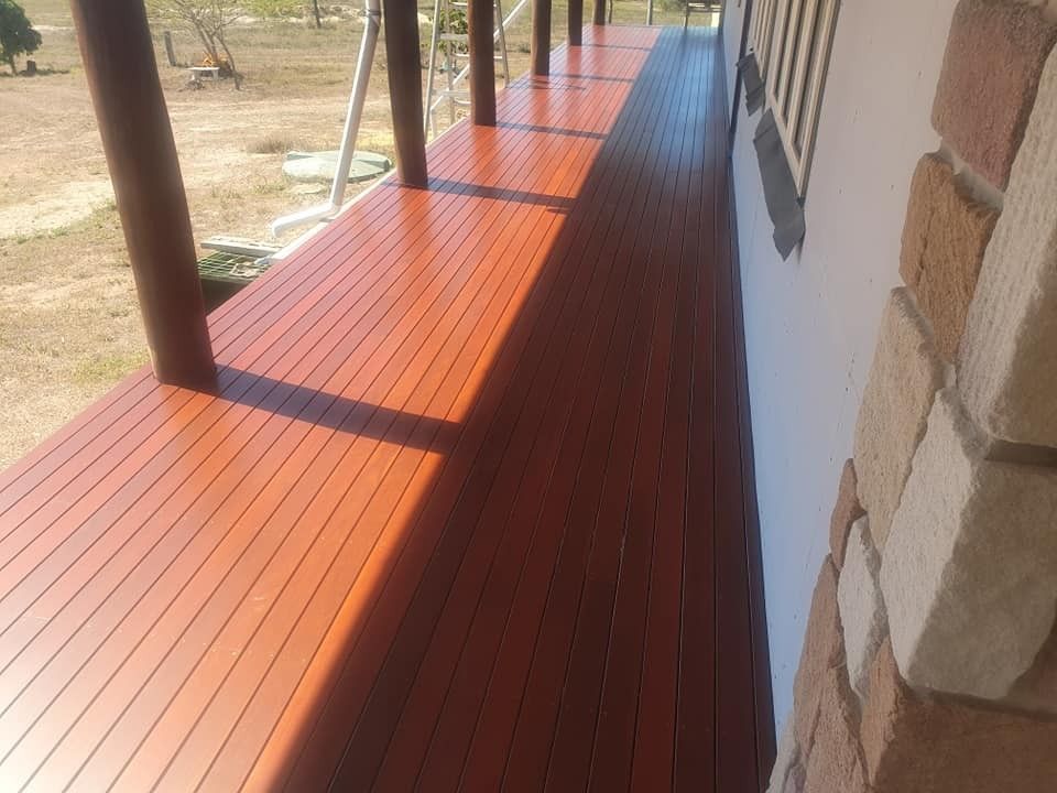 A Wooden Deck with A Brick Wall in The Background — Finish It Floor Sanding in Bucca, QLD