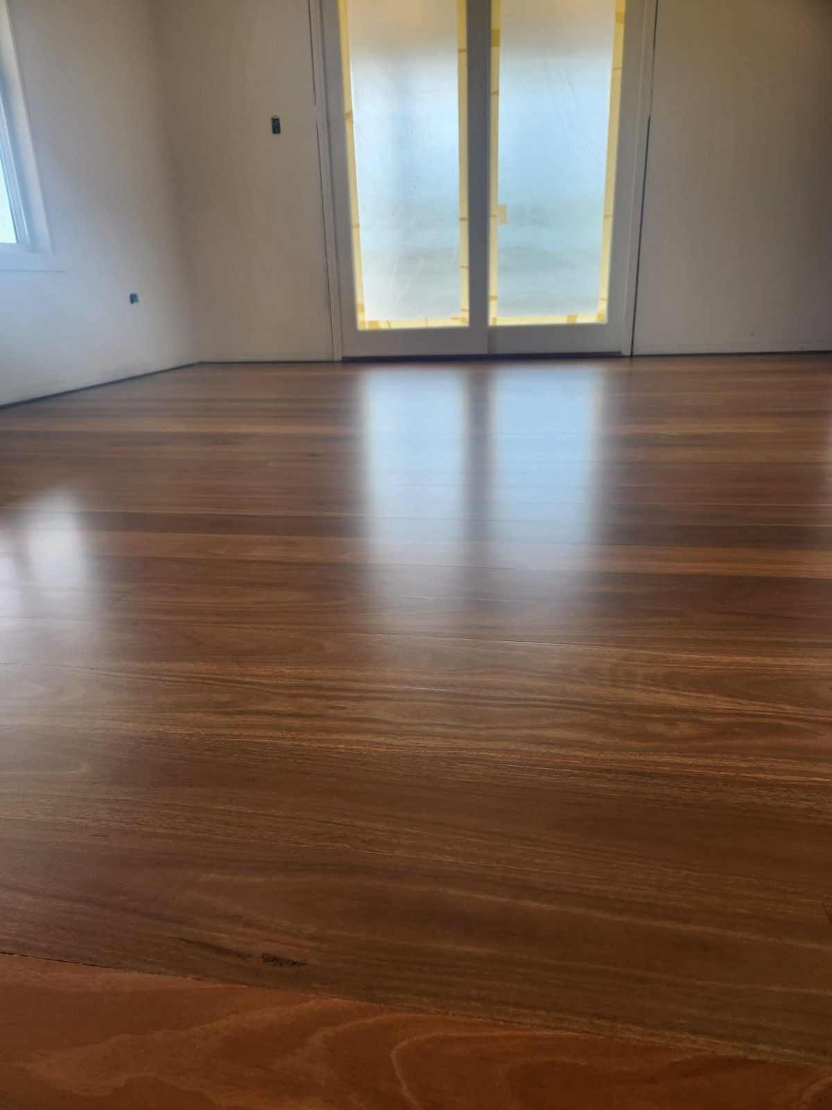 A Room with A Wooden Floor and Sliding Glass Doors — Finish It Floor Sanding in Gladstone, QLD