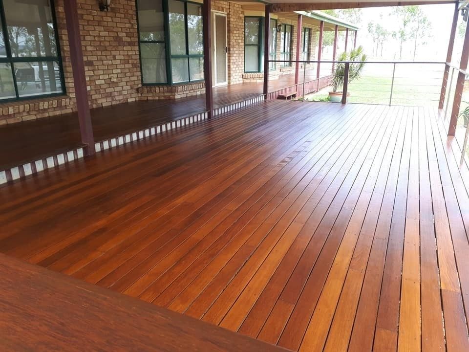 A Large Wooden Deck with A Brick House in The Background — Finish It Floor Sanding in Bucca, QLD