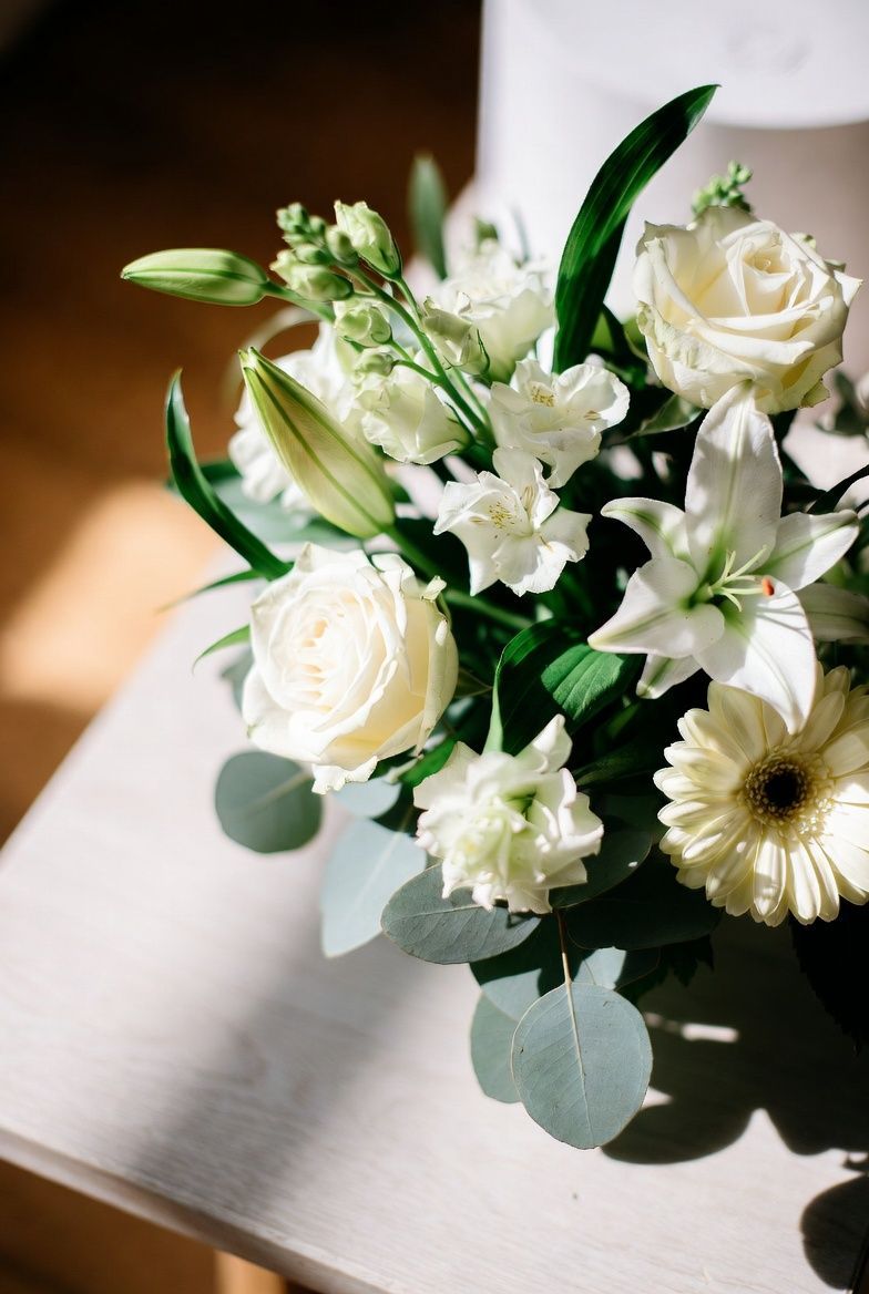 Prachtig wit rouwboeket met rozen en lelies bij een opbaring