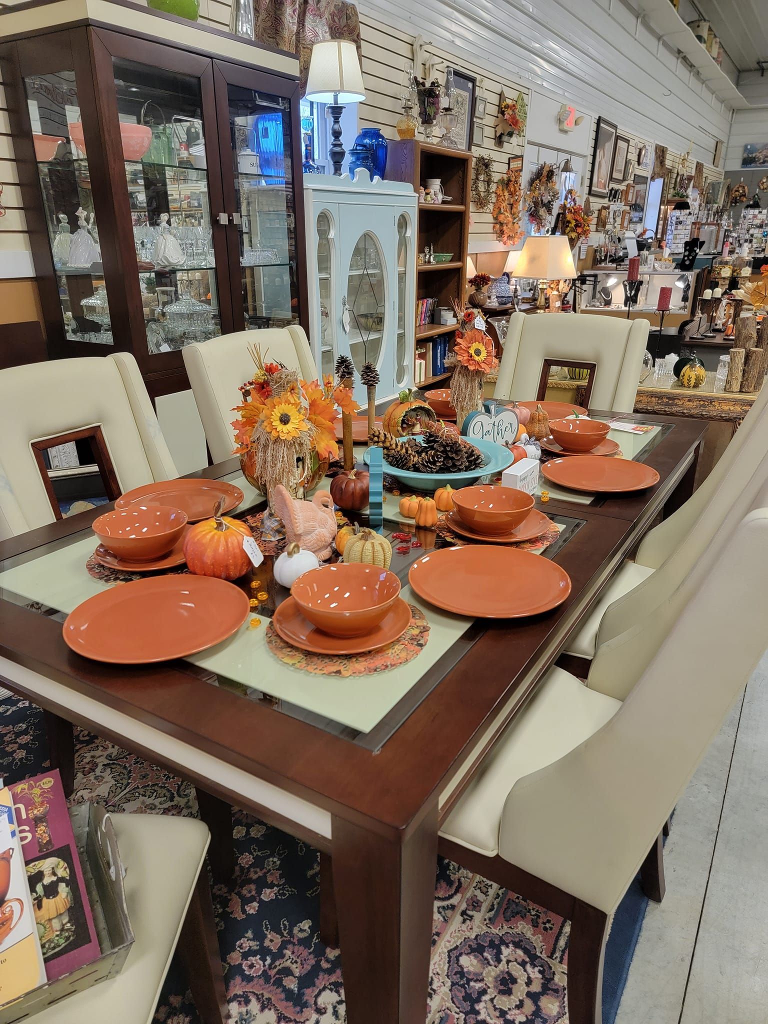 A dining room table with plates , bowls , and pumpkins on it.