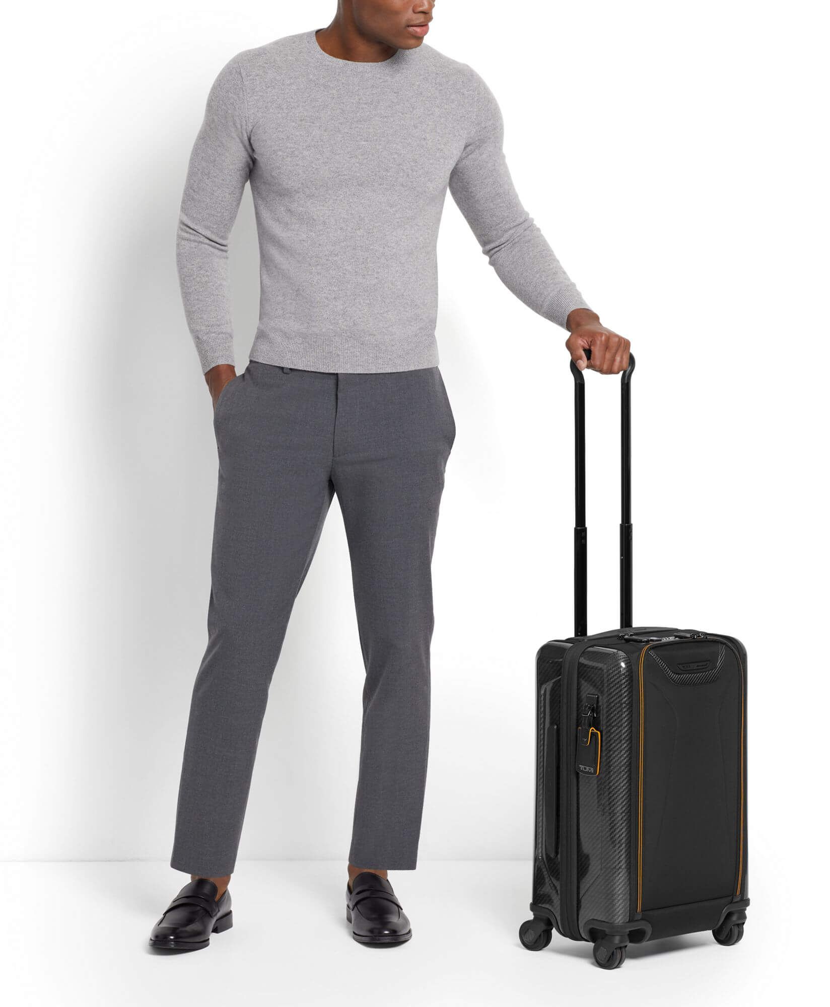 tumi mclaren carry on black with handle wheeled by man in grey outfit