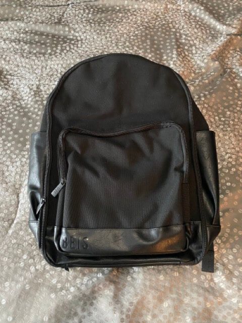 beis the backpack black backpack leather trim on bottom black zippers and pulls front zippered pocket two side storage pockets