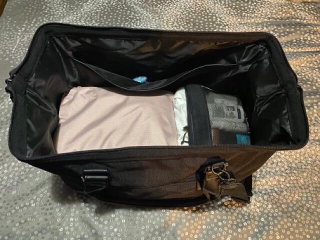 beis black the convertible weekender black bag open packed pink packing cube black toiletry organizer black bag on gray bedspread