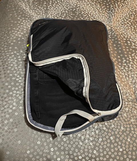 gonex black packing cube on gray bedspread gray zipper opened cube displaying black jeans and additional clothes