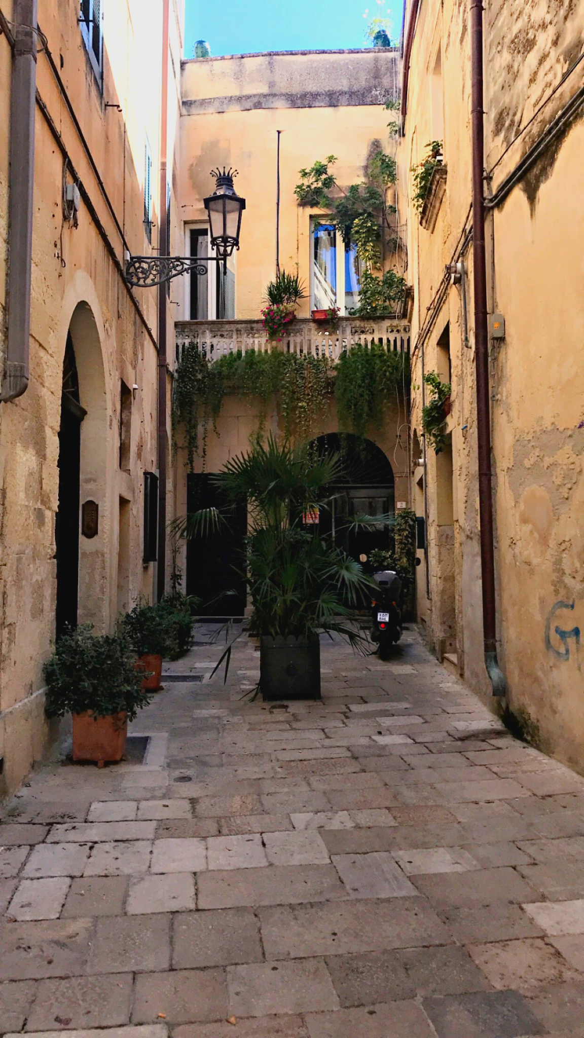 Lecce Puglia Italy alley with tan walls green plants street lamp