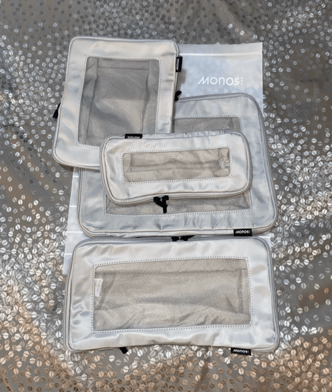 monos gray compressible packing cube set of four black monos logos and mesh inserts on each cube displayed on gray bedspread