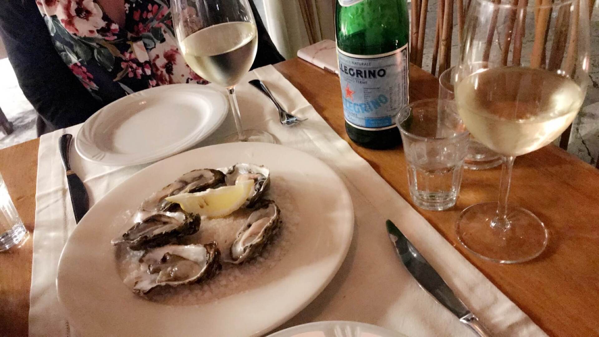 oysters on white plate restaurant two wine glasses two empty white plates