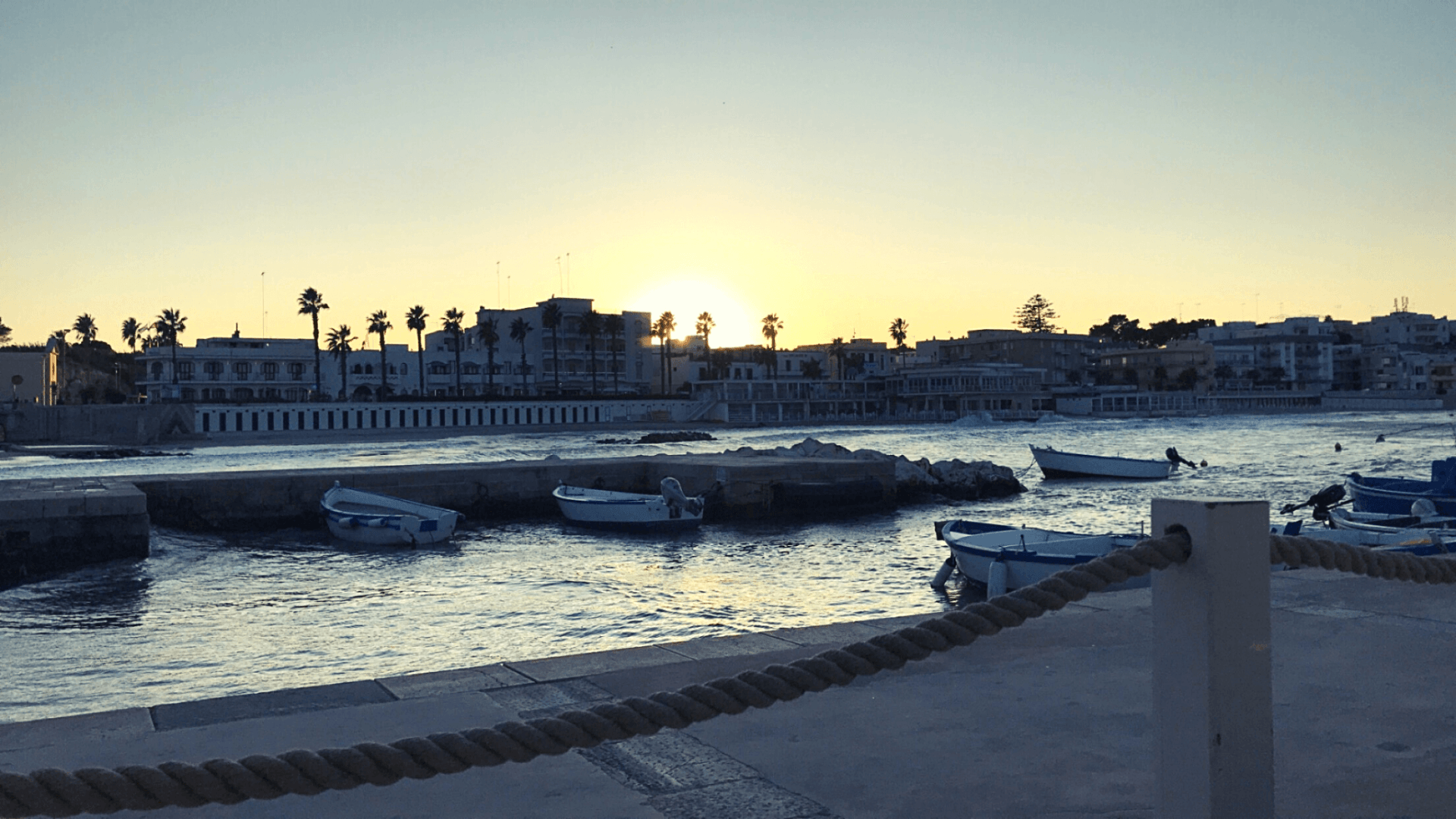 Otranto Italy waterfront promenade sunset white buildings white boats palm trees