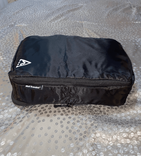 well traveled packing cube black cube closed zipper compressed well traveled logo cube on gray bedspread